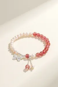 Close-up of natural pearl and red strawberry quartz bracelet with silver butterfly charm.