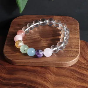 Detailansicht eines Bergkristall-Armbands mit bunten Edelsteinperlen auf Holz