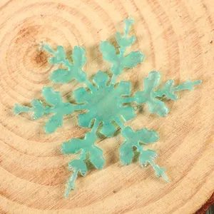 Macro view of a mint green glittery snowflake on a rustic wood slice background.