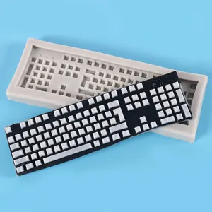 Close-up of keyboard-shaped silicone mold with finished resin model on blue background