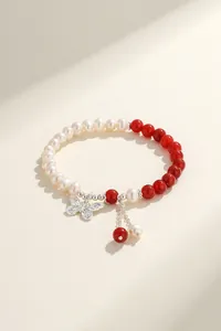 Close-up of freshwater pearl and red agate bracelet with silver butterfly charm