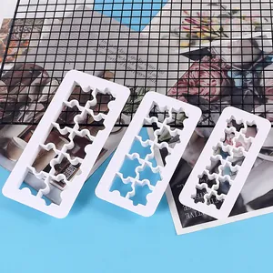 Detailed view of three white plastic puzzle-shaped baking molds on a cooling rack