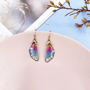 Macro view of gradient cicada wing earrings decorated with sparkling crystal rhinestones