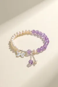 Detailed shot of a pearl and amethyst beaded bracelet with a silver butterfly charm