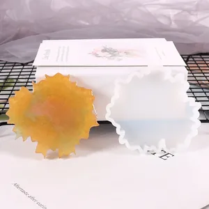 Close-up of irregular silicone coaster mold and golden glitter resin coaster on a white box