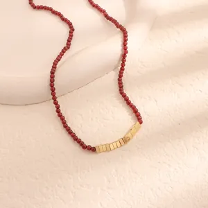 Dettaglio di collana vintage con perle di granato e accenti quadrati in metallo dorato