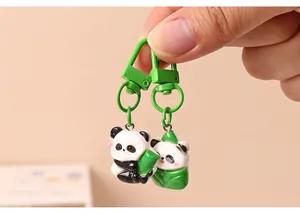 Macro view of two cute resin panda charms with green bamboo and leaf details on keychains.