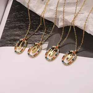 Close-up detail of gold letter necklaces with colorful zircon stones on oval pendants