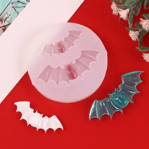 Close-up of Halloween bat shape silicone mold with finished white and teal resin bats