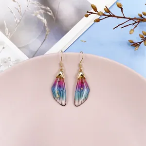 Detailed view of colorful gradient cicada wing earrings with gold foil flakes and accents