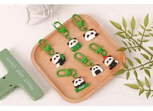 Detail view of six cute cartoon panda resin keychains on a wooden tray with green clips