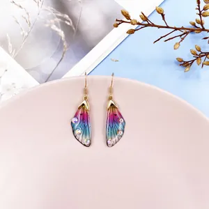 Detailed macro view of colorful gradient cicada wing earrings with sparkly rhinestones