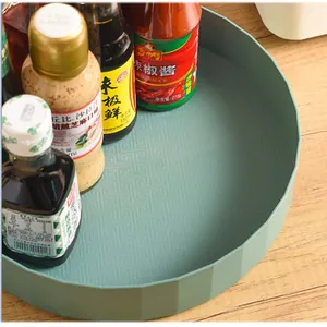 Gros plan d'un plateau de cuisine rotatif vert avec fond texturé et bouteilles d'épices