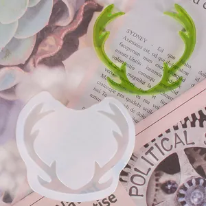 Close-up of a white silicone deer antler mold and its green transparent resin finished piece.