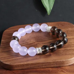 Primer plano detallado de pulsera de amatista y cuarzo ahumado en base de madera