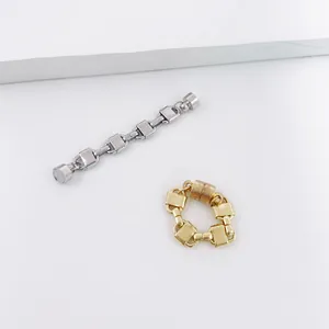 Close-up view of gold and silver magnetic chain ear cuffs on minimalist white surface