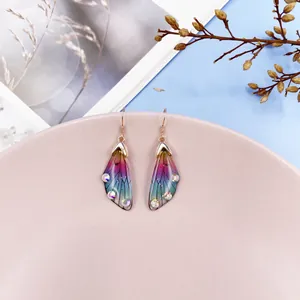 Detail view of colorful gradient cicada wing earrings with sparkling rhinestones