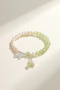 Detail view of natural freshwater pearl and green stone bracelet with butterfly charm.