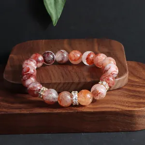 Naturrotes Phantomquarz-Perlenarmband mit glitzernden Zirkonia-Abstandshaltern auf Holz