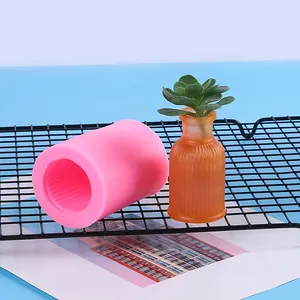 Nahaufnahme einer rosa Silikonform für Vasen neben einer fertigen orangefarbenen Vase