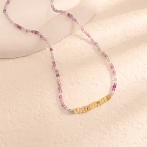 Dettaglio di una collana di perline viola con accenti di blocchi in metallo dorato.
