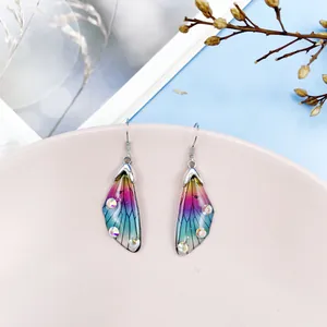 Macro view of colorful gradient cicada wing earrings with sparkling crystal rhinestones