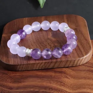 Detalle de cuentas de amatista natural y espaciadores de plata sobre madera