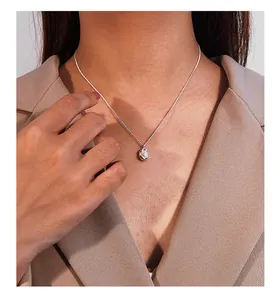 Detailed view of an irregular silver pearl pendant necklace worn with a beige blazer.