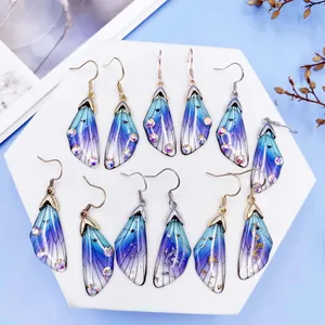 Gradient purple and blue cicada wing earrings with sparkling rhinestones on white display.