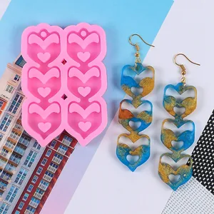 Detail shot showing the pink heart earring mold next to finished blue resin earrings.