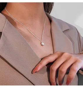 Close-up detail of a vintage irregular pendant necklace worn with a beige blazer