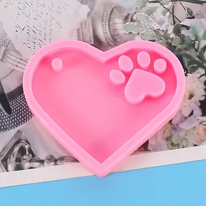 Close-up view of a pink heart-shaped silicone mold with an embossed cat paw print detail