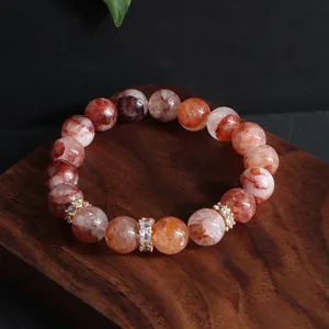 Makrodetail eines 12mm roten Hämatoid-Quarz-Kristallarmbands mit goldfarbenen Zirkon-Spacer
