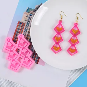 Detailed view of pink heart earring silicone mold with finished resin earrings on a plate