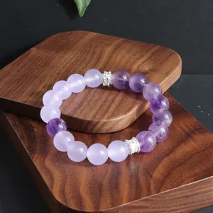 Primer plano de pulsera de amatista natural y cuarzo lavanda sobre base de madera