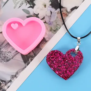 Detailed view of heart-shaped pink silicone mold and matching glittery resin pendant