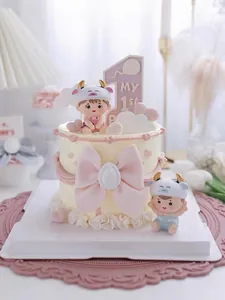 Detalle de figuras de bebés y lazo rosa en una tarta de fondant para primer cumpleaños