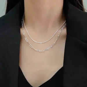 Detail of layered silver necklaces with sparkling star and paperclip chain design