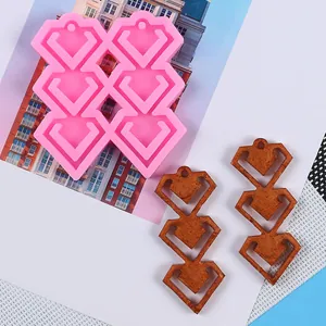 Detail view of pink heart-shaped silicone mold and finished resin earring pendants