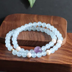 Detailweergave van een dubbelstrengs aquamarijn en kunziet armband met parels