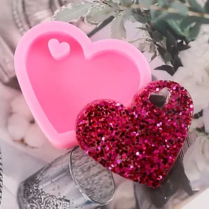 Detail view of heart-shaped silicone mold and finished glittery resin keychain charm