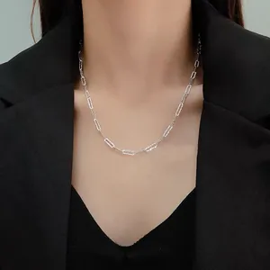 Close-up of sparkling silver paperclip chain necklace on a model in a black blazer