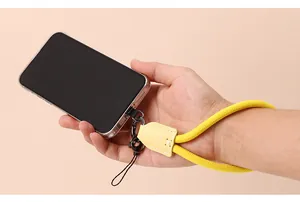 Detailed view of yellow nylon mobile phone wrist strap with leather loop worn on wrist