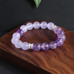 Detalle de pulsera de amatista con separadores de cristal sobre base de madera.