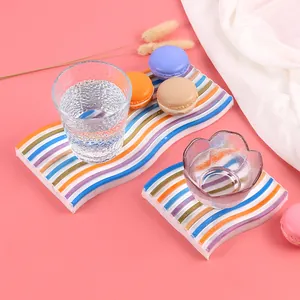 Dettaglio di sottobicchieri in silicone a onde arcobaleno con macarons e bicchieri