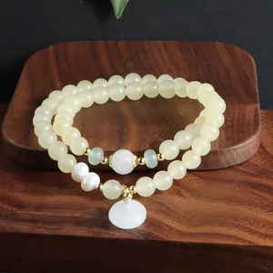 Detailansicht eines zweireihigen Jade- und Perlenarmbands mit weißem Friedensanhänger