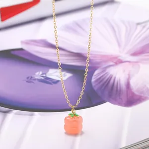 Elegant gold necklace featuring a peach-shaped orange agate pendant on a floral background.