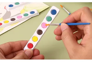 Detailed close-up shot of hands using a 6-color solid watercolor set with a blue brush