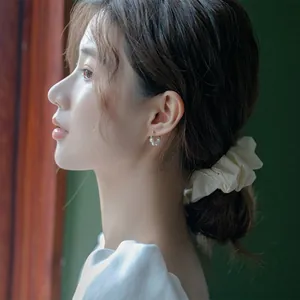 Primer plano de elegantes mini pendientes de perlas con un diseño retro atemporal