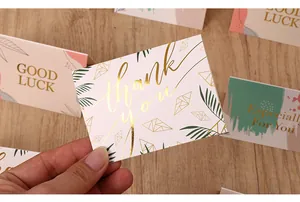 Gros plan d'une carte de vœux 'Thank You' dorée avec d'élégants motifs de feuilles.